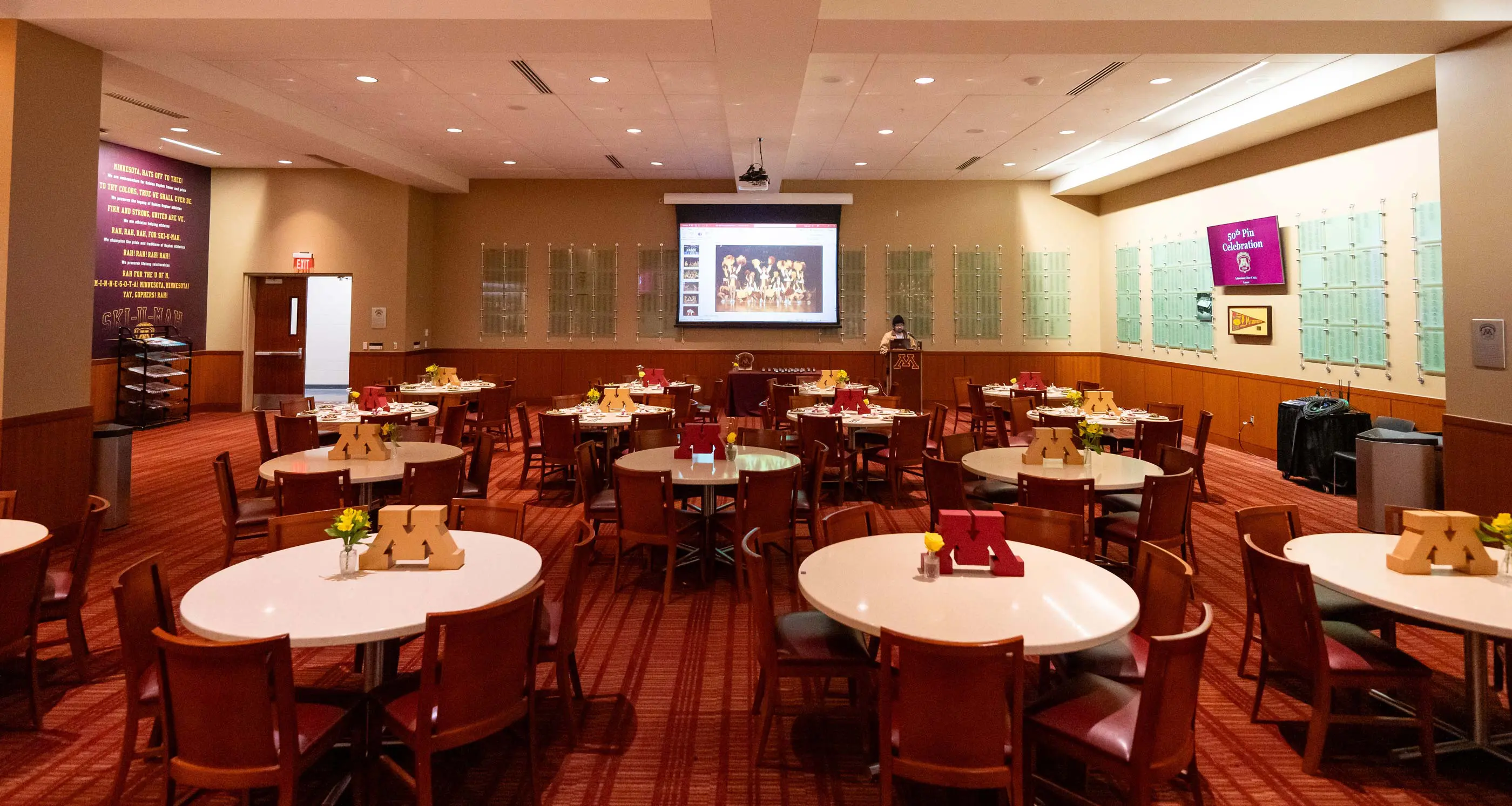 Tables set up for a pregame reception with a presentation projector and screen