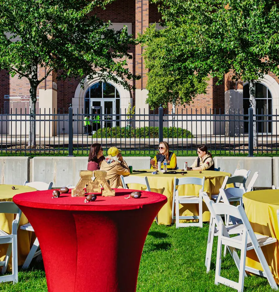 Tailgate event with people sitting at tables with food and drinks