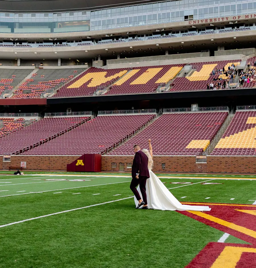 A couple walking down the football field at their wedding ceremony