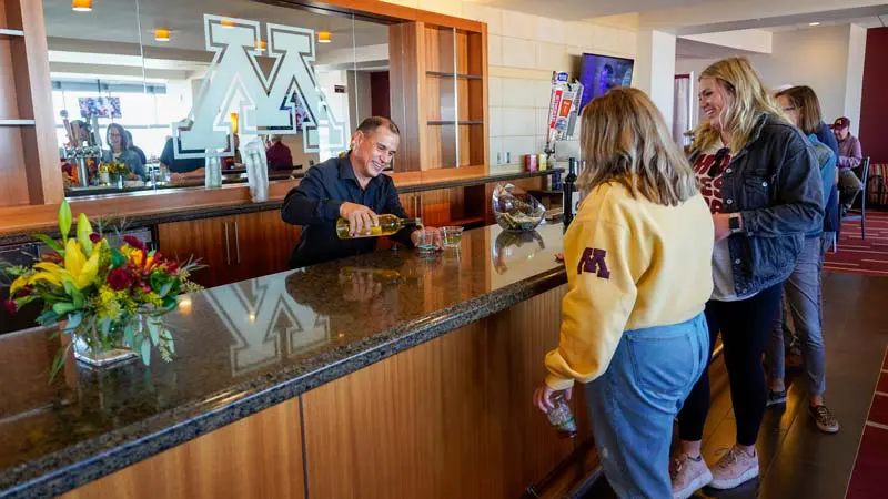 Two women at the bar while bartender makes drink